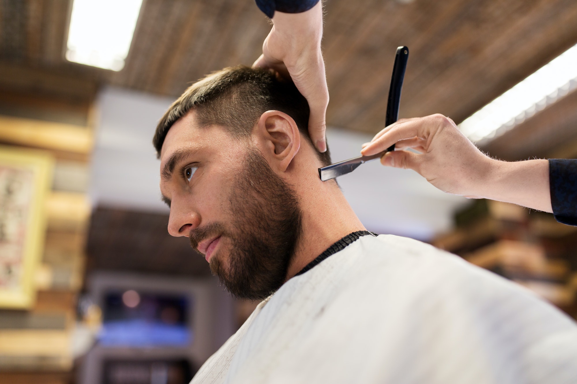 man and barber with straight razor shaving hair